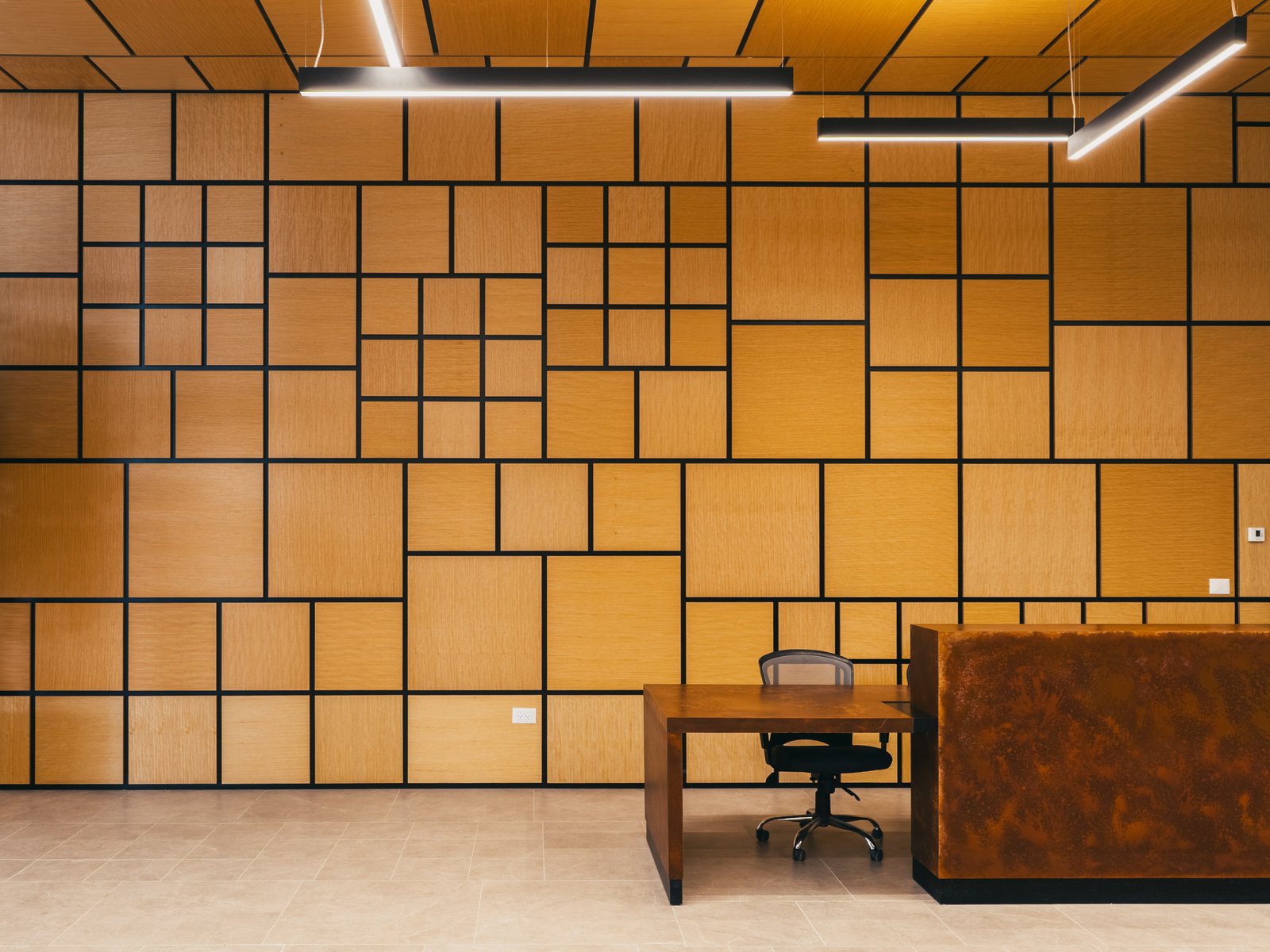 A reception hall clad floor to ceiling in a Mondrian grid of warm oak panels, with a corten-steel reception desk