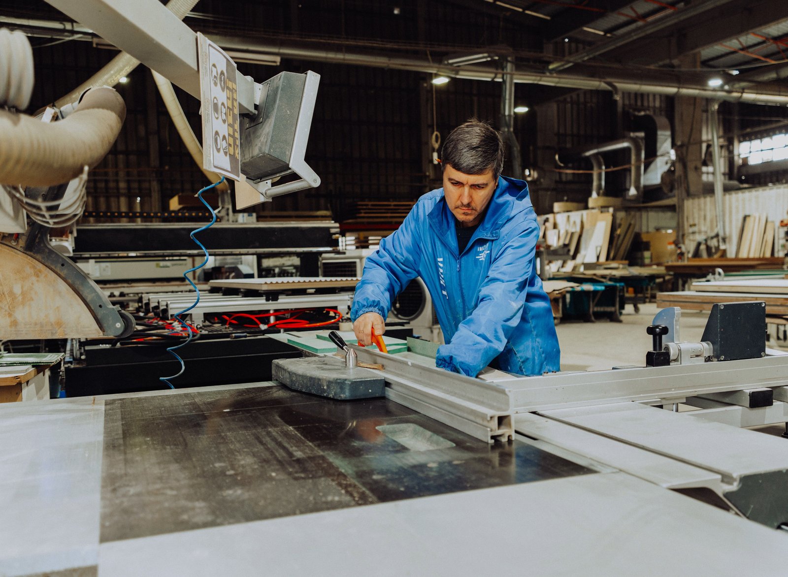 An ArtiArt craftsman operating a panel saw in the production workshop