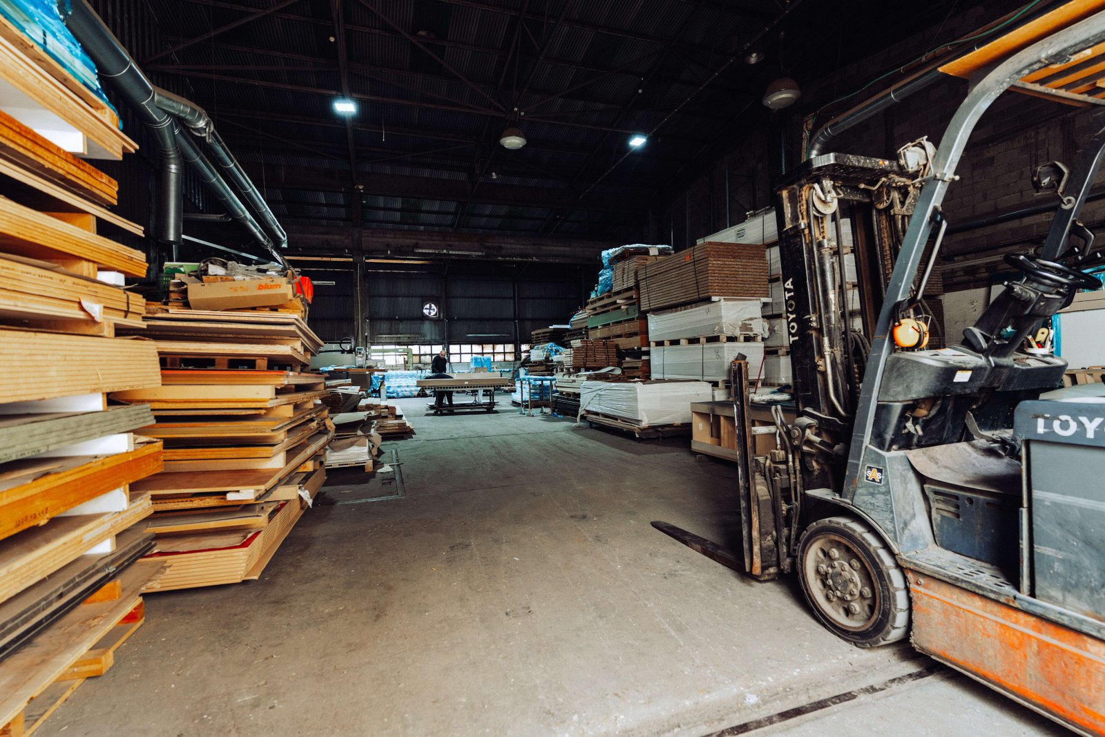 The ArtiArt workshop floor with stacked panel stock and a forklift