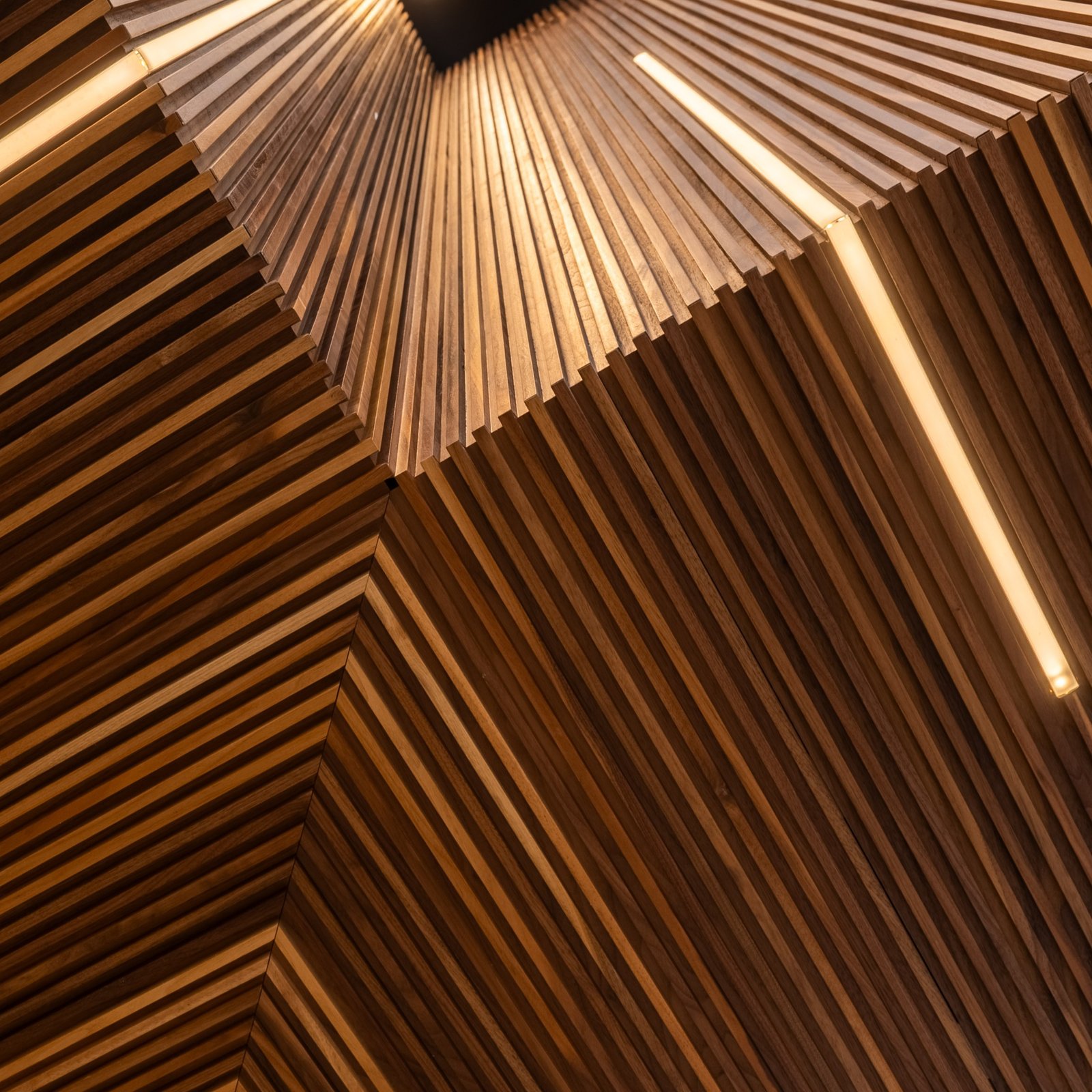 Angled walnut slat cladding with integrated linear lighting