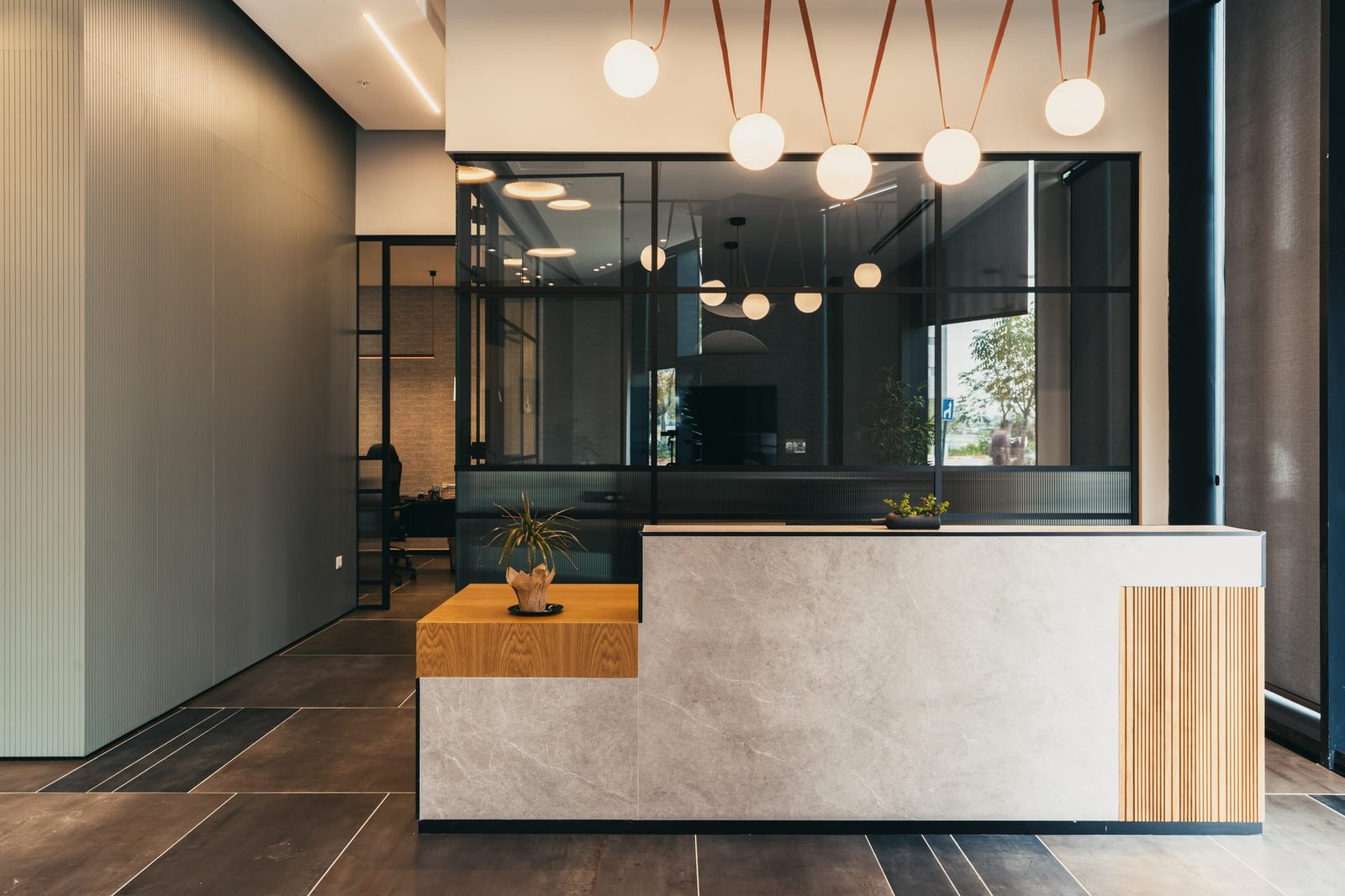 Reception desk in grey stone and oak with globe pendants